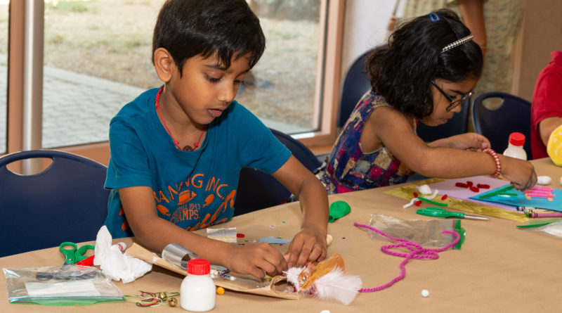 Children at table using various art supplies to make something creative