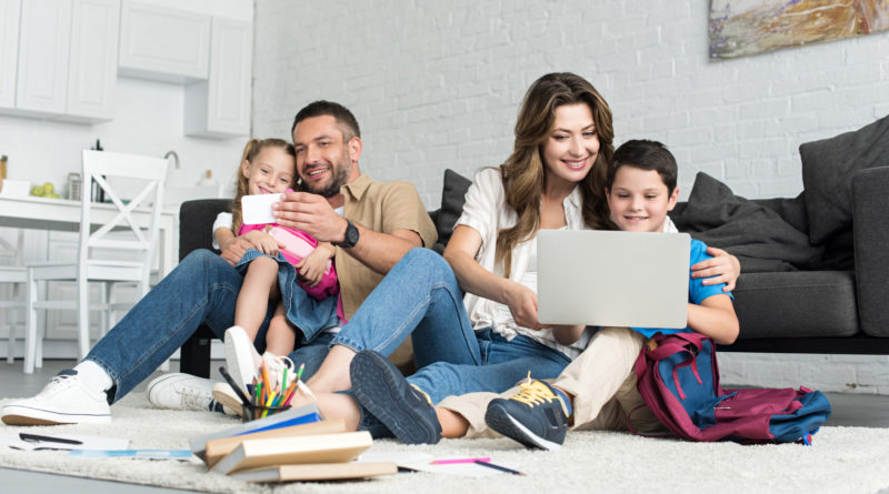 Family sitting together using laptop and phone
