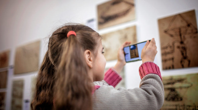 Young girl using a phone to explore a museum