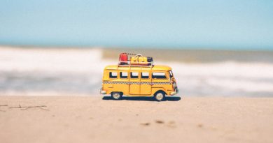 Tiny toy bus with luggage on the sand in front of water